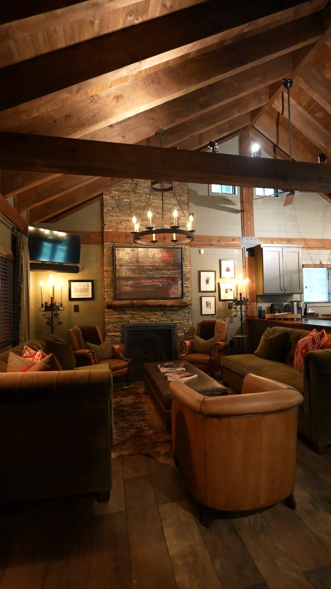 The great room with timber beams and a stone fireplace, from the cabin film