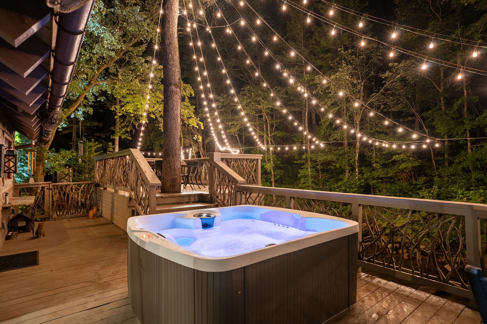 Private hot tub on a riverfront cabin deck under string lights near Jones Gap State Park